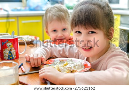 boy girl children eat at the table eating dinner laugh