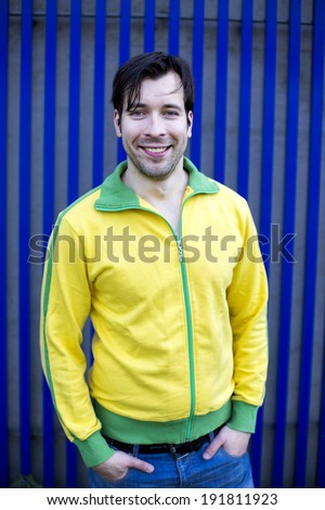 portrait of man in yellow sports jacket in front of blue wall