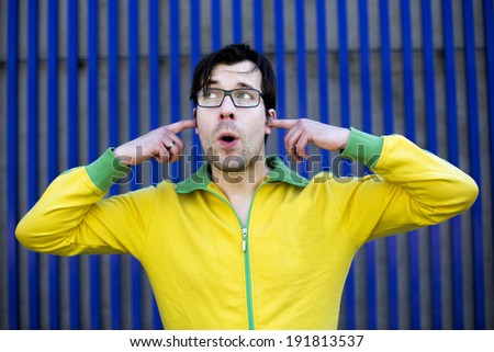 man in yellow sports jacket shuts his ears with his fingers and pretends not to hear anything