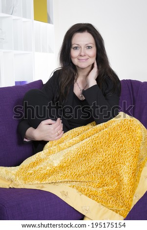 woman sitting on purple couch with yellow blanket