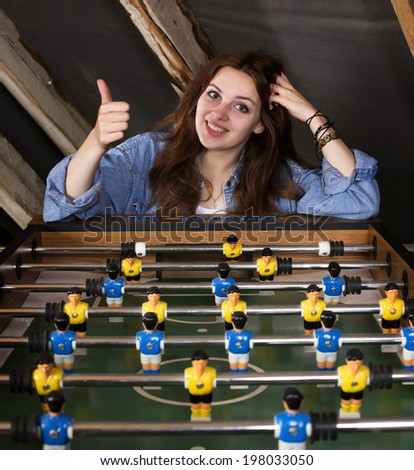 girl at a table football ,smiling and holding thumbs up