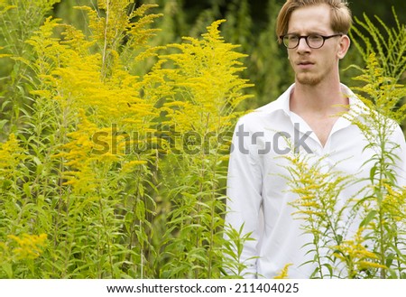 portrait of a young man in a white shirt standing in a park