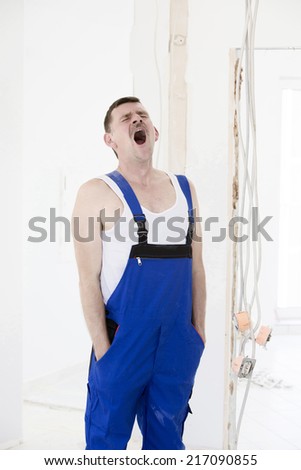 repairman in a boiler-suit is yawning