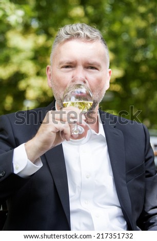 man in a suit holding a glass of wine