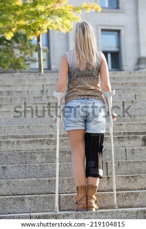 blonde woman with crutches standing on stairs