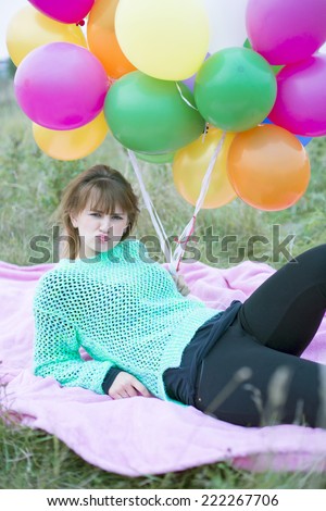 young woman laying on grass with a bunch of balloons
