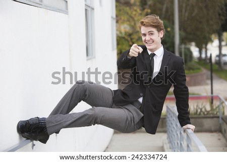 man in a suit jumping at a wall and pointing his finger