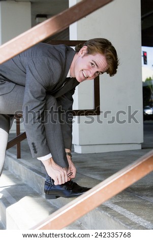 businessman outside at stairs ties his shoelaces
