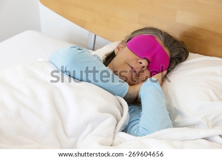 older woman lying in bed and sleeping peacefully with a sleep mask on