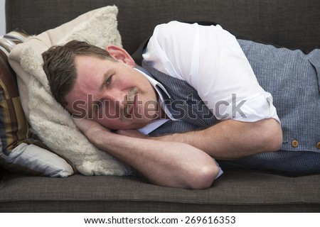 handsome man in his 50\'s lying on couch and smiling at camera