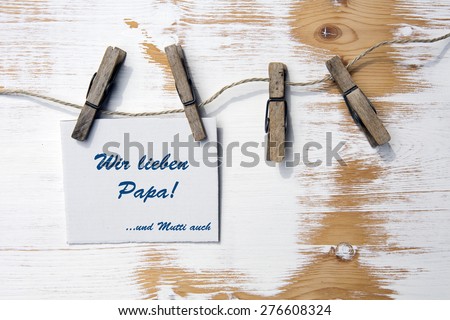 sign on a clothes line with german text:Wir lieben Papa...und Mutti auch (we love Dad and Mom too)