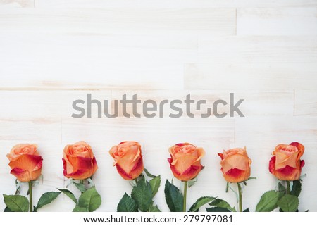 beautiful orange roses  lined up in a row on a white vintage wooden background