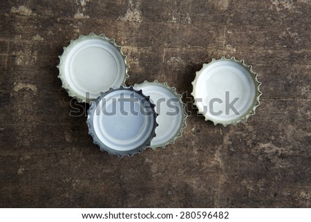 four bottle caps on a rustic wooden board