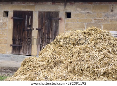 an old wooden barn door with a haystack in front of it