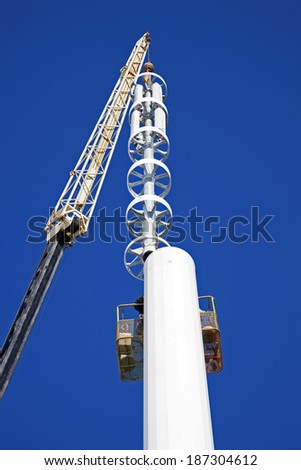 Assembilig cell tower with the crane - installation of the top part with stelath cell antennas.