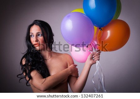 sensual brunette woman holding six balloons looking to the side studio portrait