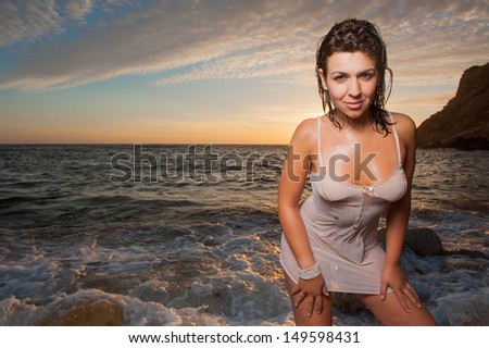 beautiful sexy brunette woman wet on the water at sunset