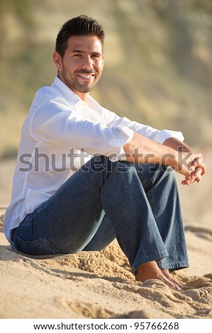 smiling man at the beach seated on the sand