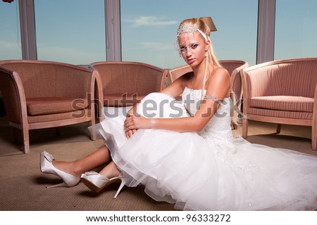 beautiful young blonde bride seated on the hotel floor
