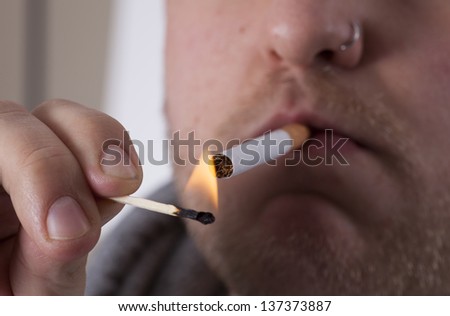 male lighting a cigarette with a match