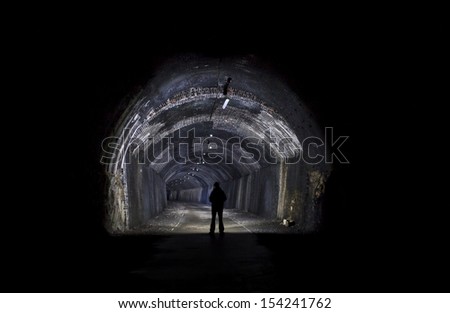 silhouette of man in a tunnel with a torch