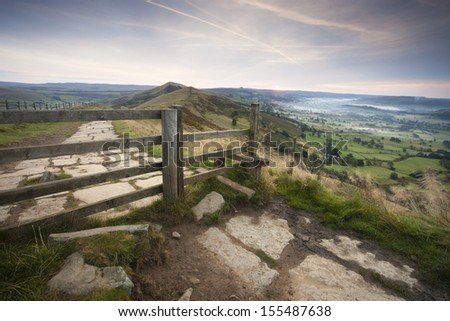 fence and gate up mountain with lovely view over hope valley at sunrise, peak district, derbyshire