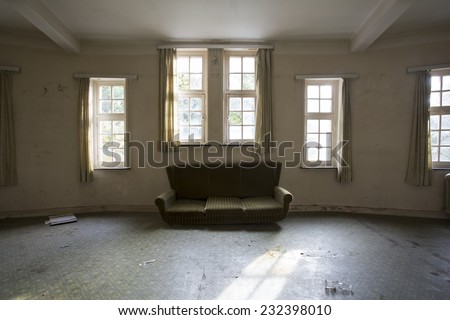 sofa chair in empty creepy room by windows