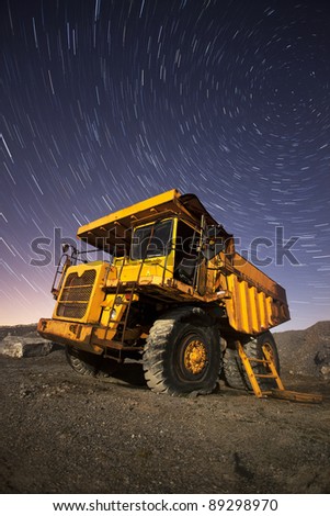 old veichle in an abandoned scrap yard at night with star trails
