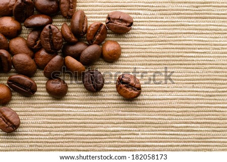 Backgrounds and textures: dark roasted coffee beans scattered on rough canvas surface