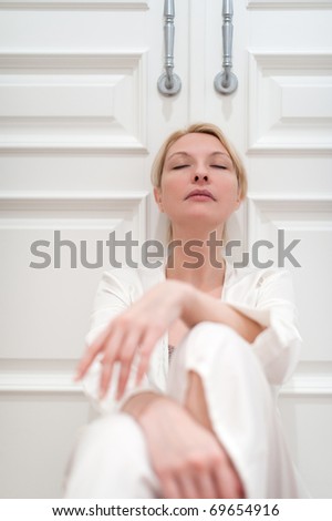 Beautiful young woman portrait, white silk bathrobe, white doors as background, focus on a face