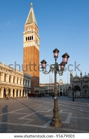 Early morning at the Piazza San Marco (St Mark\'s Square). Campanile San Marco, National Library building and famous Venetian street-lamp.