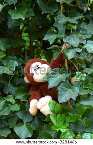 cute stuffed animal monkey swinging in tree with ivy