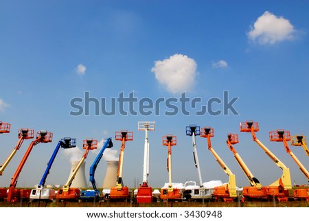 colorful articulating construction boom lifts with power plant on background