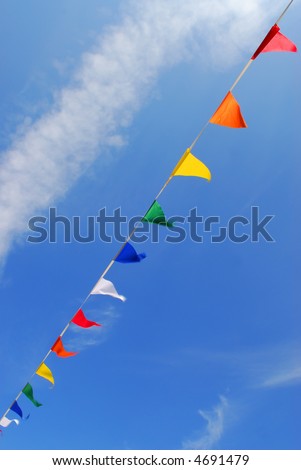 multi colored party flags on a line on a background of blue sky with fluffy white clouds