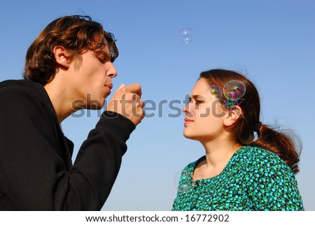 Concept: stay young! Man in his twenties blowing soap bubbles to his girlfriend