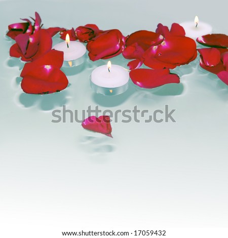 Romantic red rose petals and burning white candles floating on water with square background and heart shaped petal on foreground