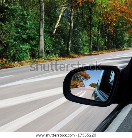 Forest autumn landscape in the sideview mirror of a speeding car on square background