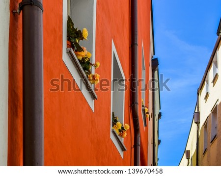 red and yellow house wall between an alleyway with flowers