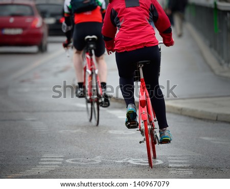Persons on bikes seen from behind, in rain