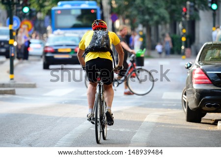 Man with helmet bicycling in traffic
