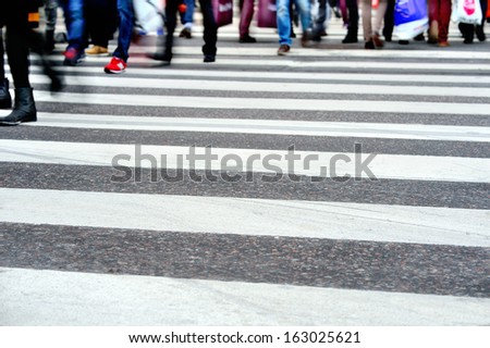 Motion blurred pedestrians crossing sunlit street