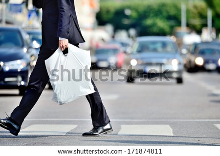 Man in suit with plastic bag crossing street