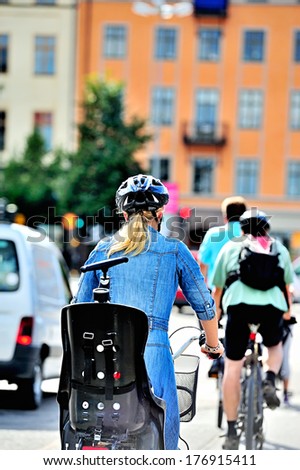Woman with helmet biking, city apartment buildings in the background