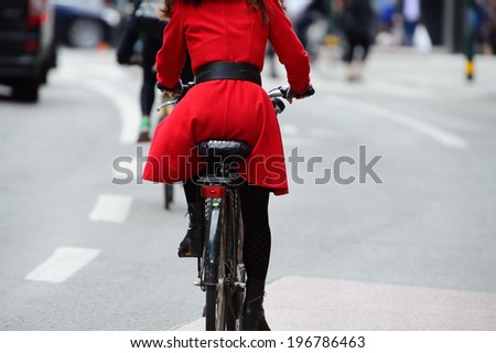 Woman in red on bike. Bike lane symbols on ground.