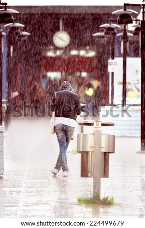 Woman in heavy rain on train station platform