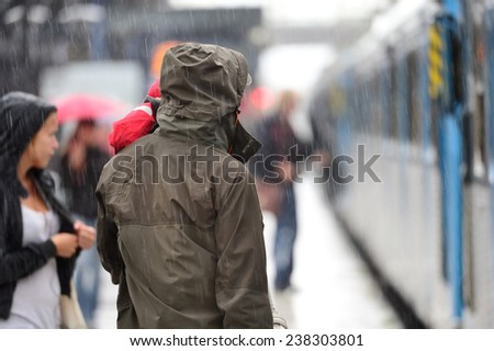 Man in raincoat in heavy rain on train station platform