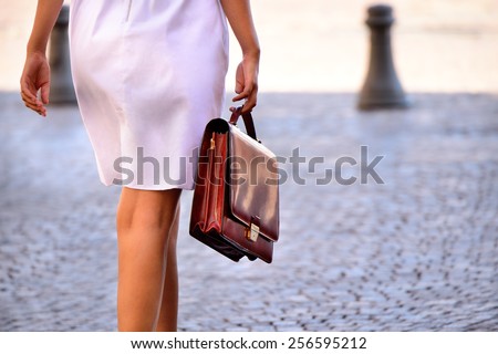 Woman walking home after work with portfolio bag