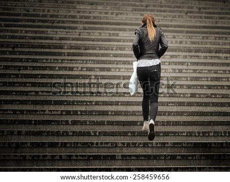 Young adult woman walks up the stairs (in the rain)