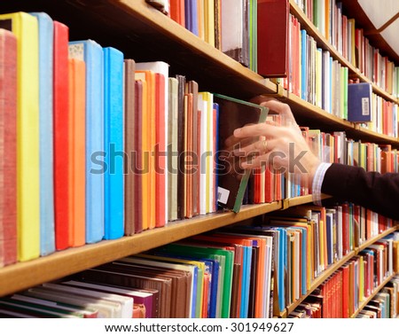 Motion blurred hand picking book in library bookshelf
