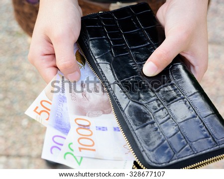 Hand holding new swedish bank notes and wallet. NOTE: the new 2015 model.